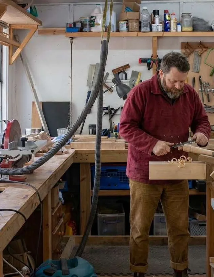 Mike working at a bench in his workshop, surrounded by hand tools
